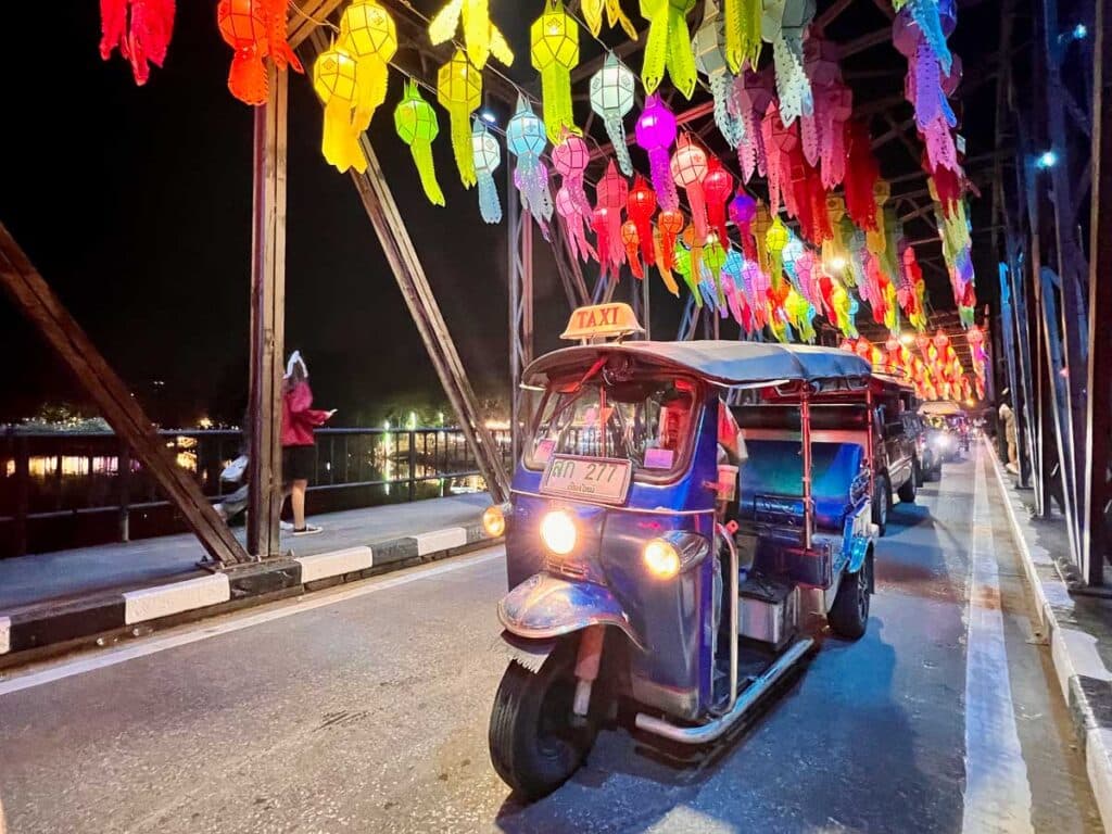 Tuk-tuk taxi driving through a Thai town at night